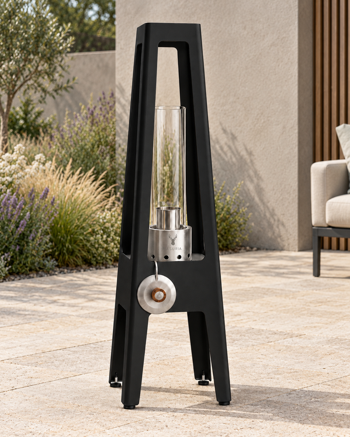 TORRE Black bioethanol lamp with metal legs on an outdoor terrace in daylight.