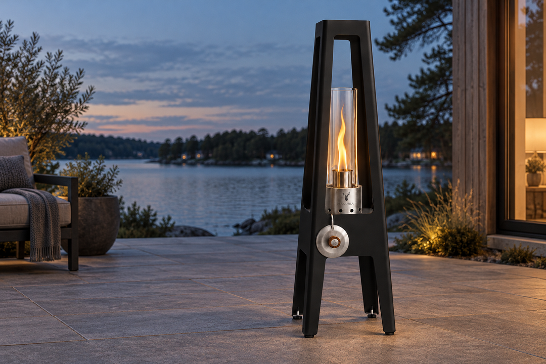 TORRE Black bioethanol lamp with metal legs with a flame on an outdoor terrace in the evening.